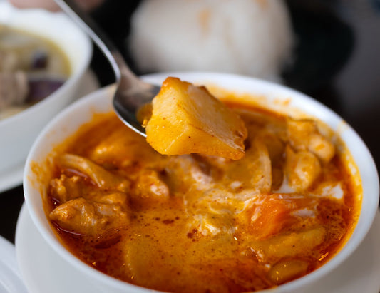 A white bowl full of a Aloo Sabzi, an Indian potato curry
