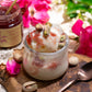 Decadent bowl of ice cream topped with organic rose petal jam, a jar of which is displayed open in the background.