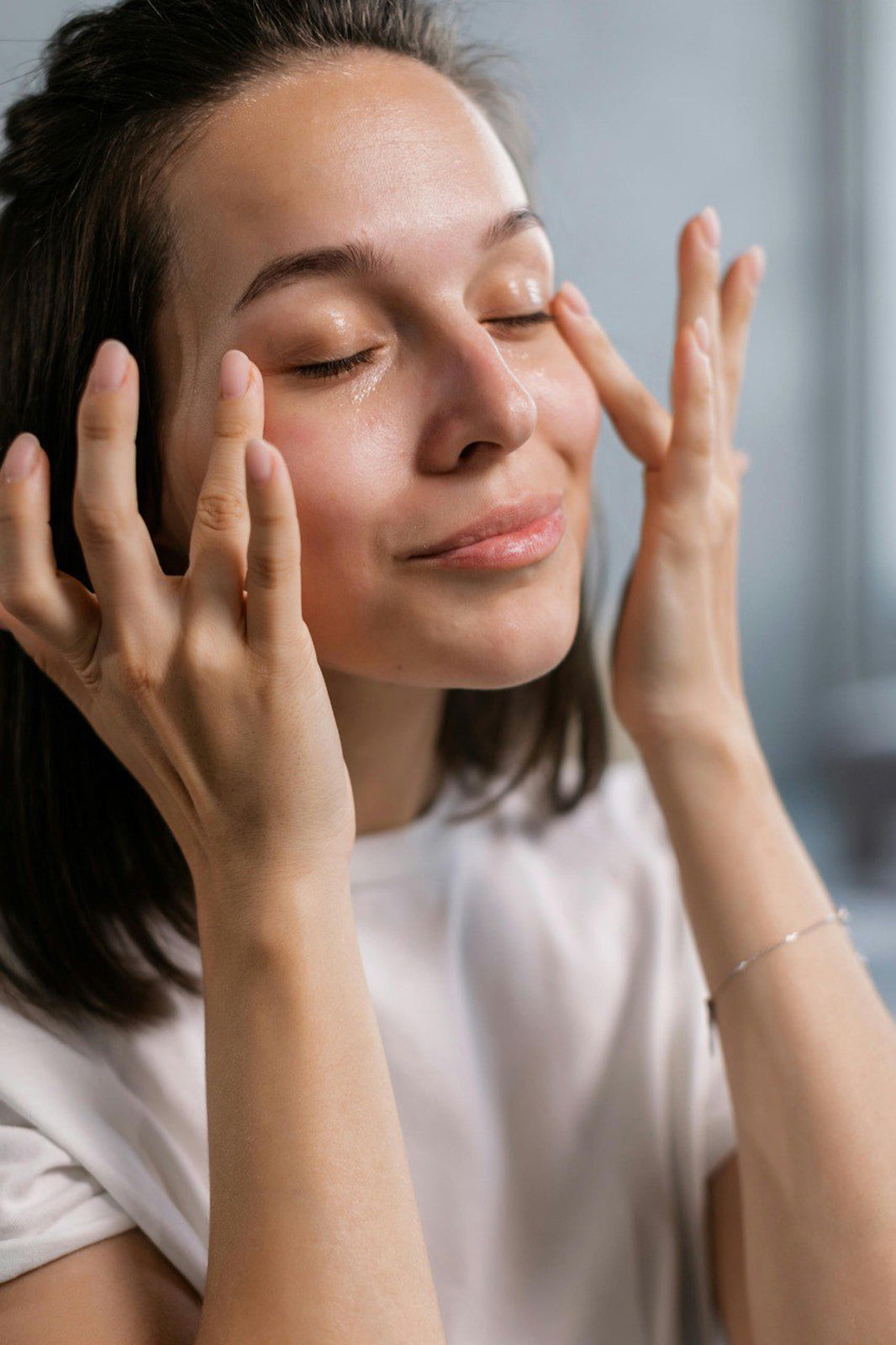 woman with a peaceful, blissful expression gently applies our Kumkumadi oil to her face