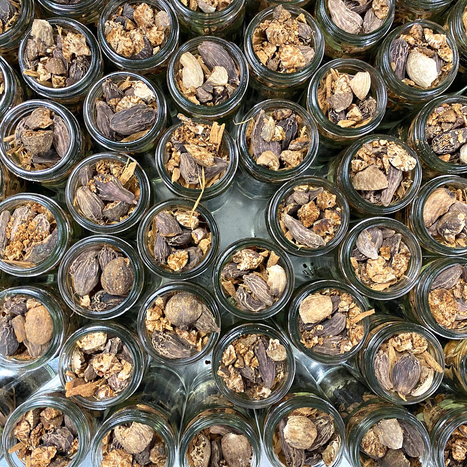 Birds eye view of multiple jars of Organic Whole Garam Masala waiting to be sealed.