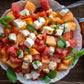 Summer salad of cubed canteloupe, watermelon, cheese, with honey and basil and featuring our Pure Indian Foods KICK Hot Sauce, an organic Mango Ghost pepper hot sauce.