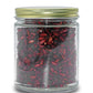 Deep red organic dried pomegranate arils packed in a clear glass jar with a brass colored lid.