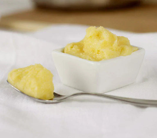 a spoonful of ghee in front of a square white bowl of ghee