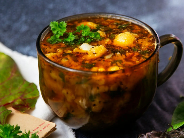 a clear bowl of sausage potato kale soup in a tomato chicken broth