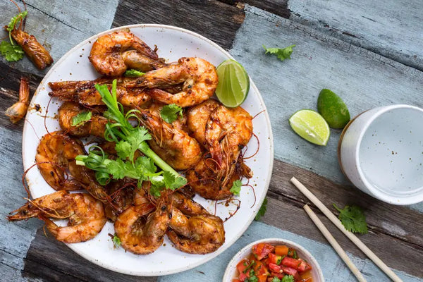 tamarind marinated sweet and sour shrimp on a whitle plate served with lime slices
