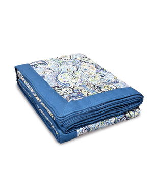 Folded blue and white patterned handmade blanket made with upcycled cotton on a white background