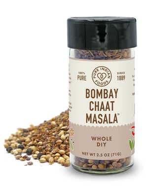 A jar of Organic Bombay Chaat Masala from Pure Indian Foods in front of a small pile of the whole spices on a white background.