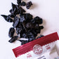 A bag of Pure Indian Foods Organic Kokum, opened and showing the dried, black kokum bits spilled onto a white surface.