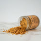 An open jar of Pure Indian Foods Organic Ladoo in a Jar spilling onto a marble counter.