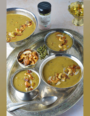 Several silver dishes filled with cooked payasam with a jar of Pure Indian Food organic cardamom pods