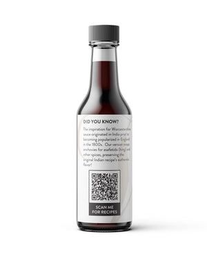 A bottle of Hing Recipe Vegan Worcestershire sauce with a dark label and a gray cap, shown on a clean white background with a soft shadow.