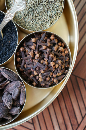 Birds eye view of organic cloves in a brass masala dabba