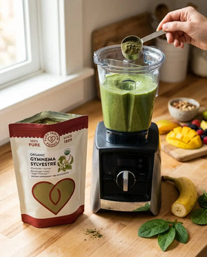 An open bag of Pure Indian Foods Organic Gymnema Sylvestre powder pictured next to a fruit smoothie being blended