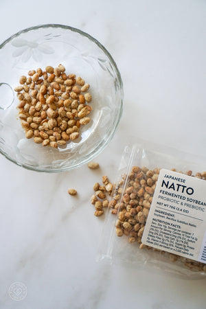 A bag of Pure Indian Foods freeze-dried natto, opened with some of the non-gmo natto spilling on to the surface and more of it in a glass bowl.