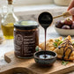 An image of a spoonful of kokum chutney being drizzled into a small bowl and over some samosas featuring a jar of Pure Indian Foods Organic Kokum Chutney in the foreground