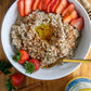 A bird's eye view of a bowl of organic sprouted buckwheat cooked with honey and cinnamon served with sliced strawberries