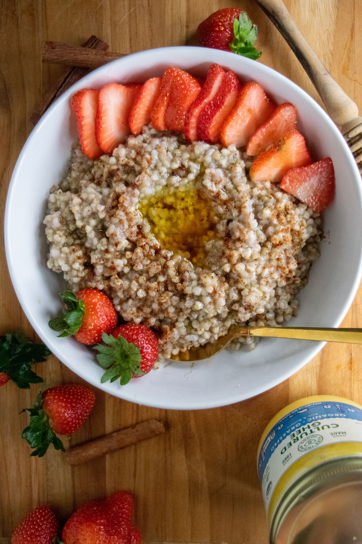 A bird's eye view of a bowl of organic sprouted buckwheat cooked with honey and cinnamon served with sliced strawberries