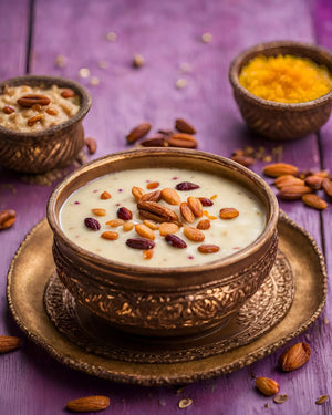 A cooked bowl of our organic kashmiri saffron kheer Mix with almonds raisins Cardamom and coconut flakes in a brass bowl on a purple wooden surface.