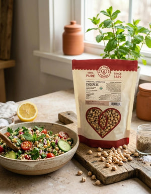 A bag of Pure Indian Foods Organic Sprouted Chickpease next to a bowl of chickpea and quinoa salad