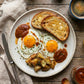 Plate of eggs, toast, and potatoes with a drizzle of our Organic Tomato Chutney on a wooden table.