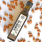 Birds-eye view of a bottle of Cold-Pressed Almond Oil from Pure Indian Foods. Certified Organic. Surrounded by a scattering of almonds.