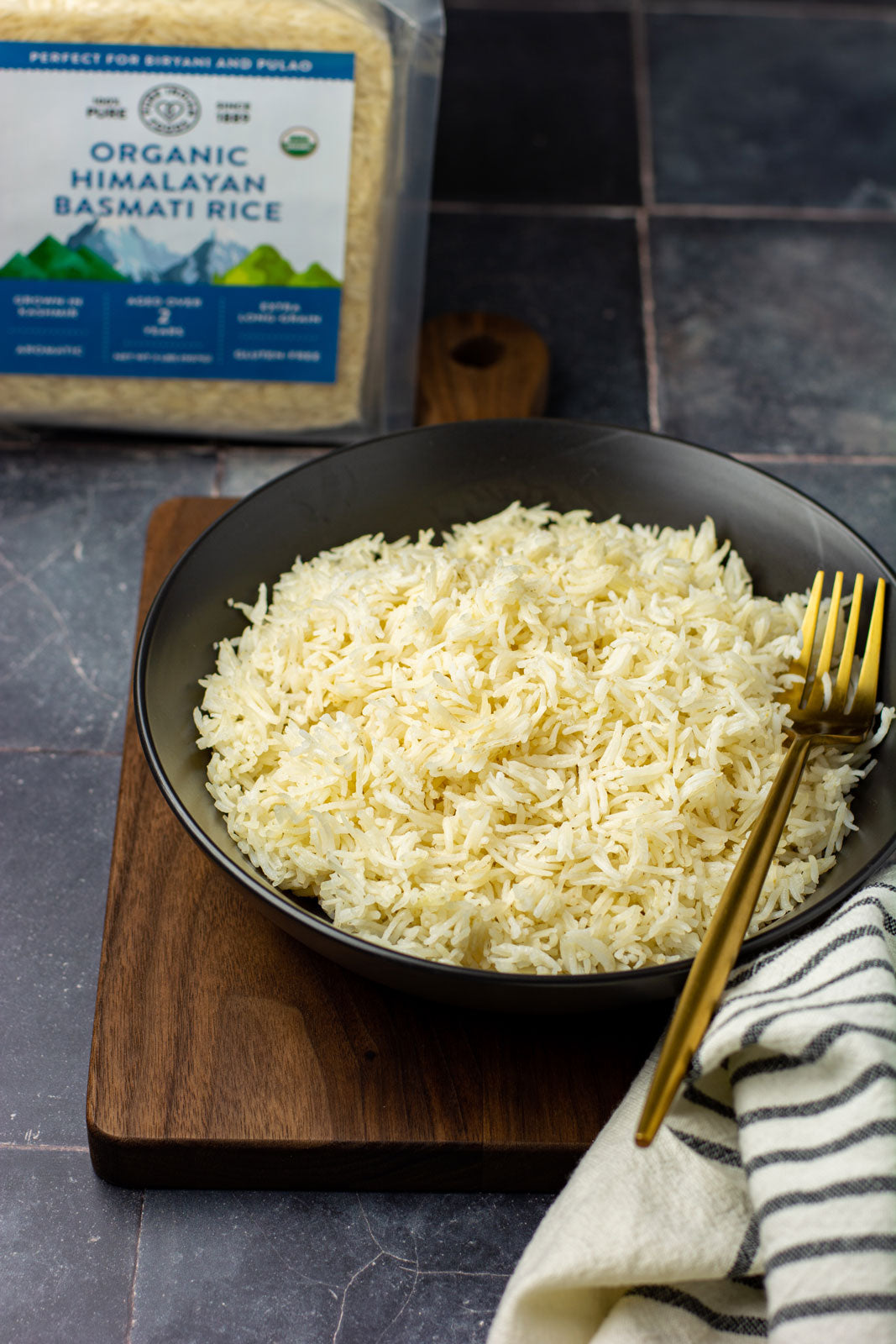 A cooked bowl of organic basmati rice from Pure Indian Foods with a package of the himalayan rice in the background.