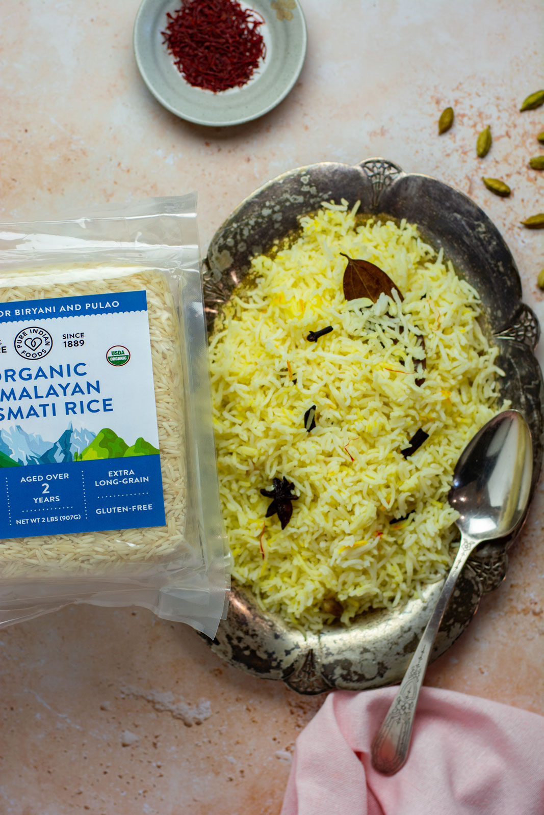 A bown of seasoned Indian rice made from Pure Indian Foods Organic Basmati Rice seasoned with our Organic Kashmiri Saffron. A package of the himalayan rice is next to it.