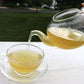 Glass teapot full of freshly brewed CCF Tea pouring a serving into a glass teacup.