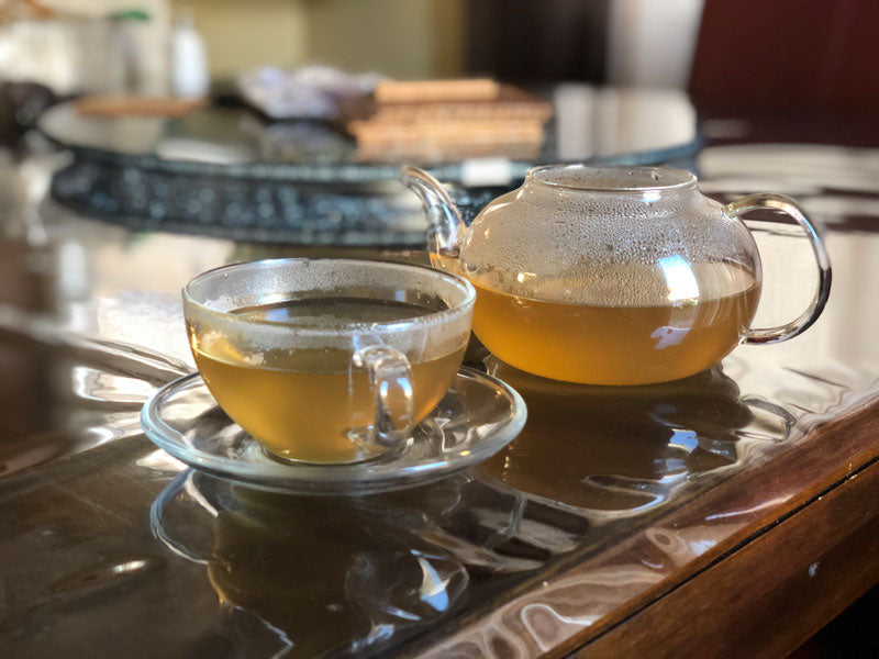 Glass teapot and teacup filled with recently brewed ayurvedic tea.