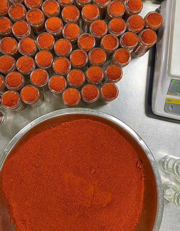 Kashmiri red chili powder being bottled by hand in small-batches.