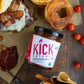 A jar of spicy ketchup from Pure Indian Foods, next to a drool-worthy burger, handmade onion rings, and fries. Certified organic.