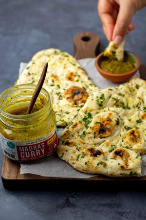 Garlic naan being dipped in our organic Indian simmer sauce.