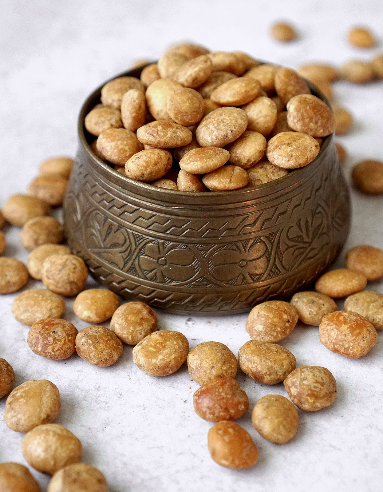 A small brass bowl is filled with sacha inchi seeds from Pure Indian Foods, and a handful of the incan seeds are also scattered around the filled bowl.