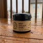 Jar of the Best Shilajit Ever, a pure shilajit resin sourced from the himalayas, sitting on a wooden deck in the rain.