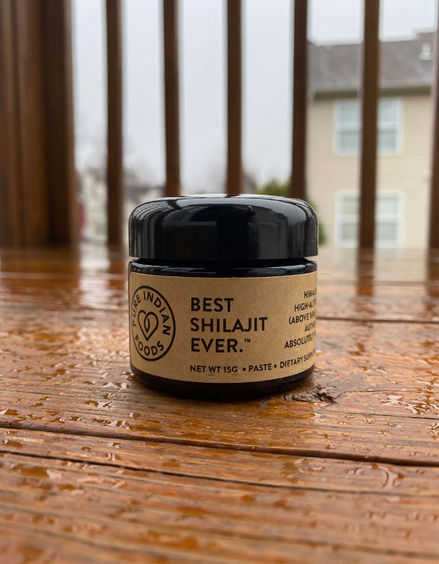 Jar of the Best Shilajit Ever, a pure shilajit resin sourced from the himalayas, sitting on a wooden deck in the rain.