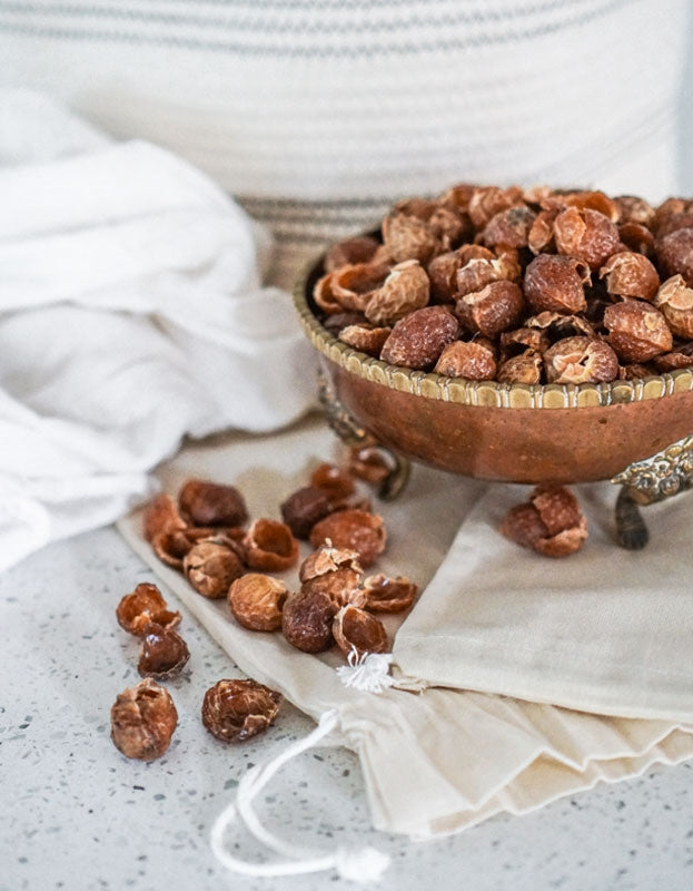 Bowl of organic soap nuts from Pure Indian Foods with a muslin bag for laundry.