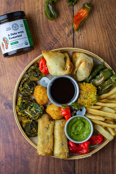 Birds eye view of a tray of appetizers served with the organic tamarind chutney made with dates by Pure Indian Foods.