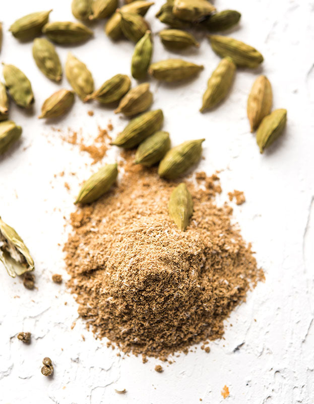 Beautifully scattered organic green cardamom pods and powder from Pure Indian Foods.