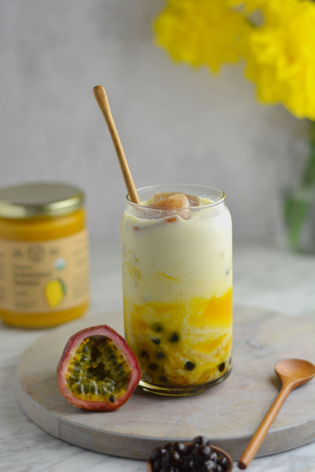 alphonso mango boba drink with a jar of organic alphonso mango puree containing 100% pure organic mango pulp in the background